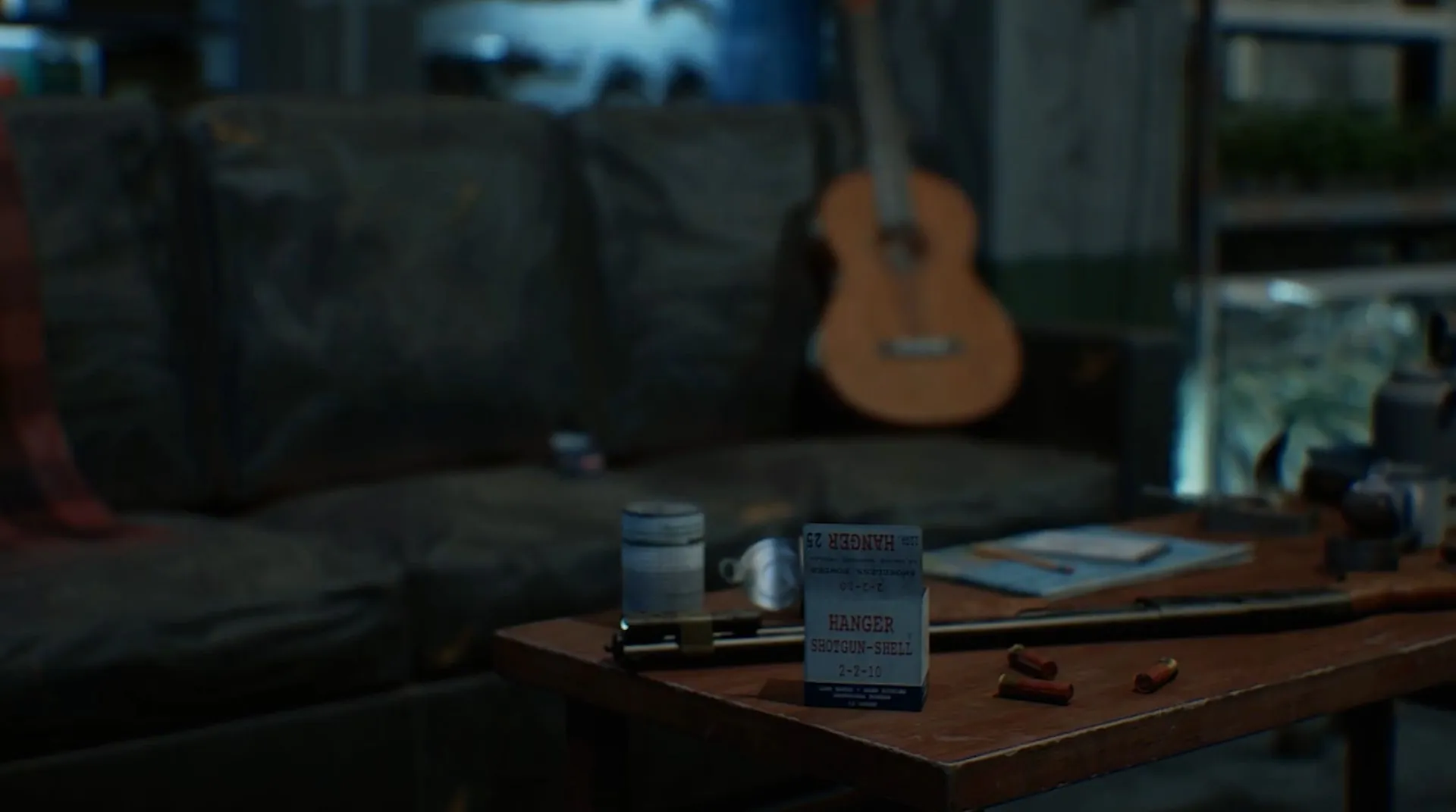 A dim, lived-in room: a worn sofa, a guitar on the wall and a cluttered table