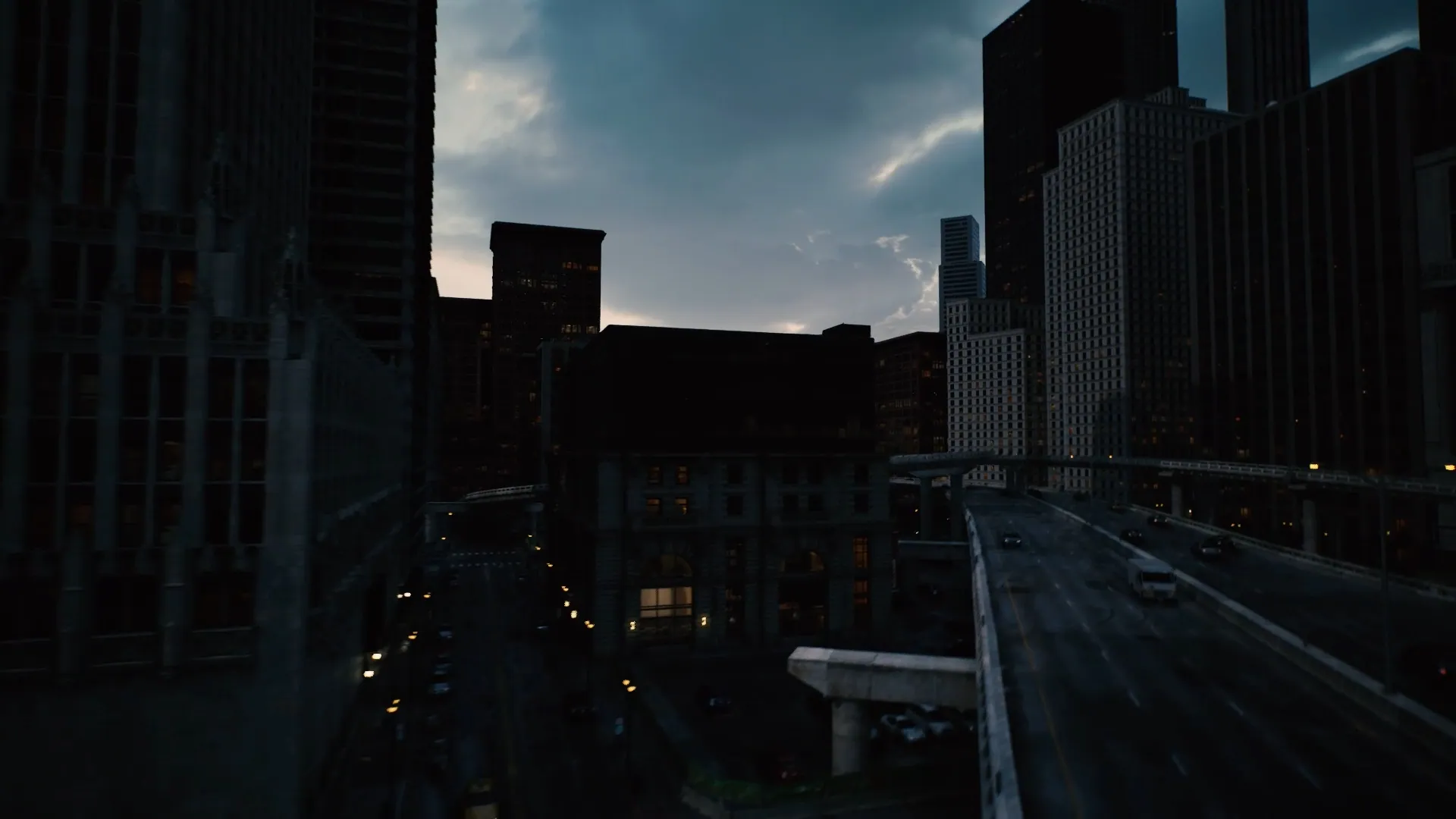 An elevated road curving between dark towers under a stormy sky