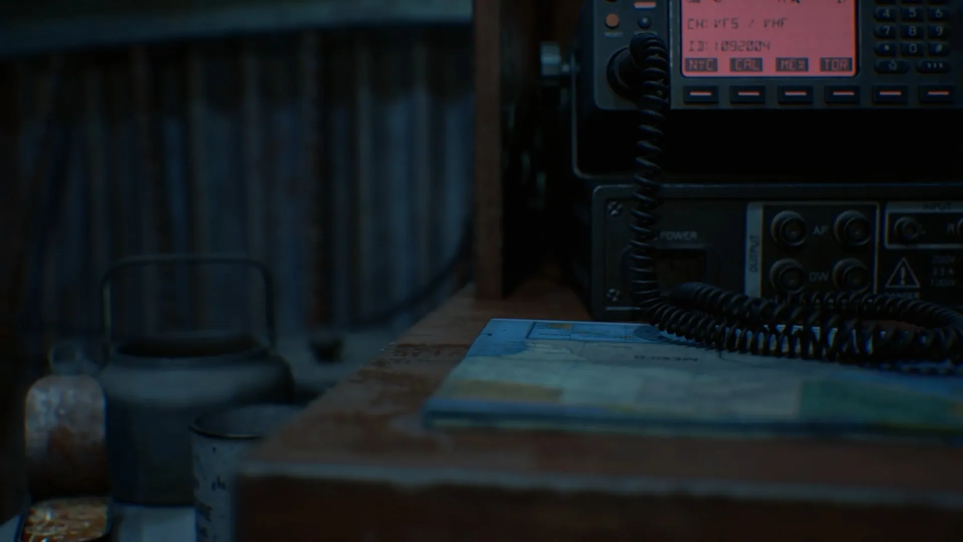 A dim radio room: an old transceiver, maps and papers on a desk