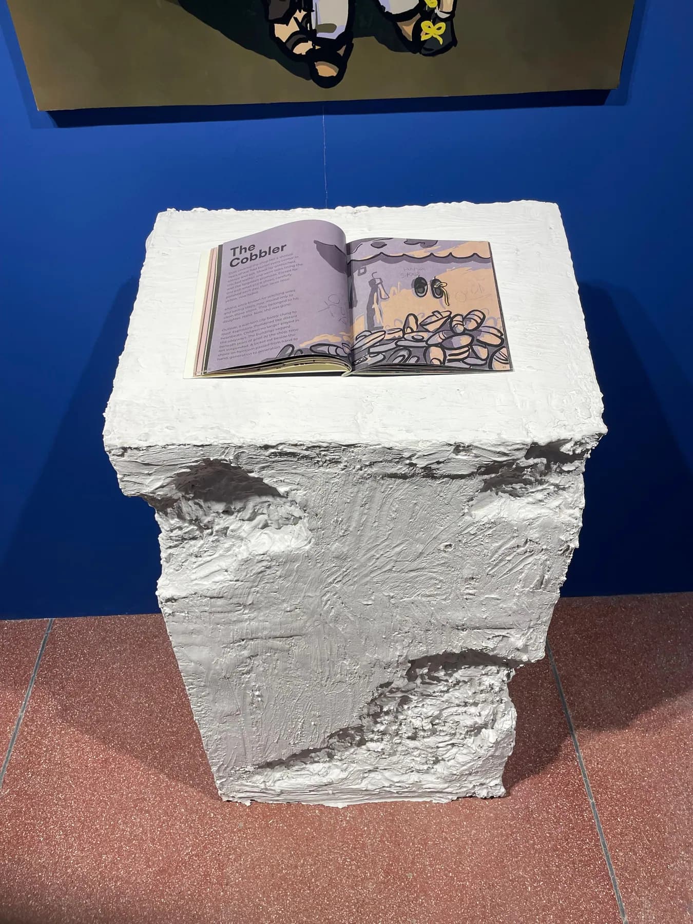 The graphic novel open on a rough, cast white plinth