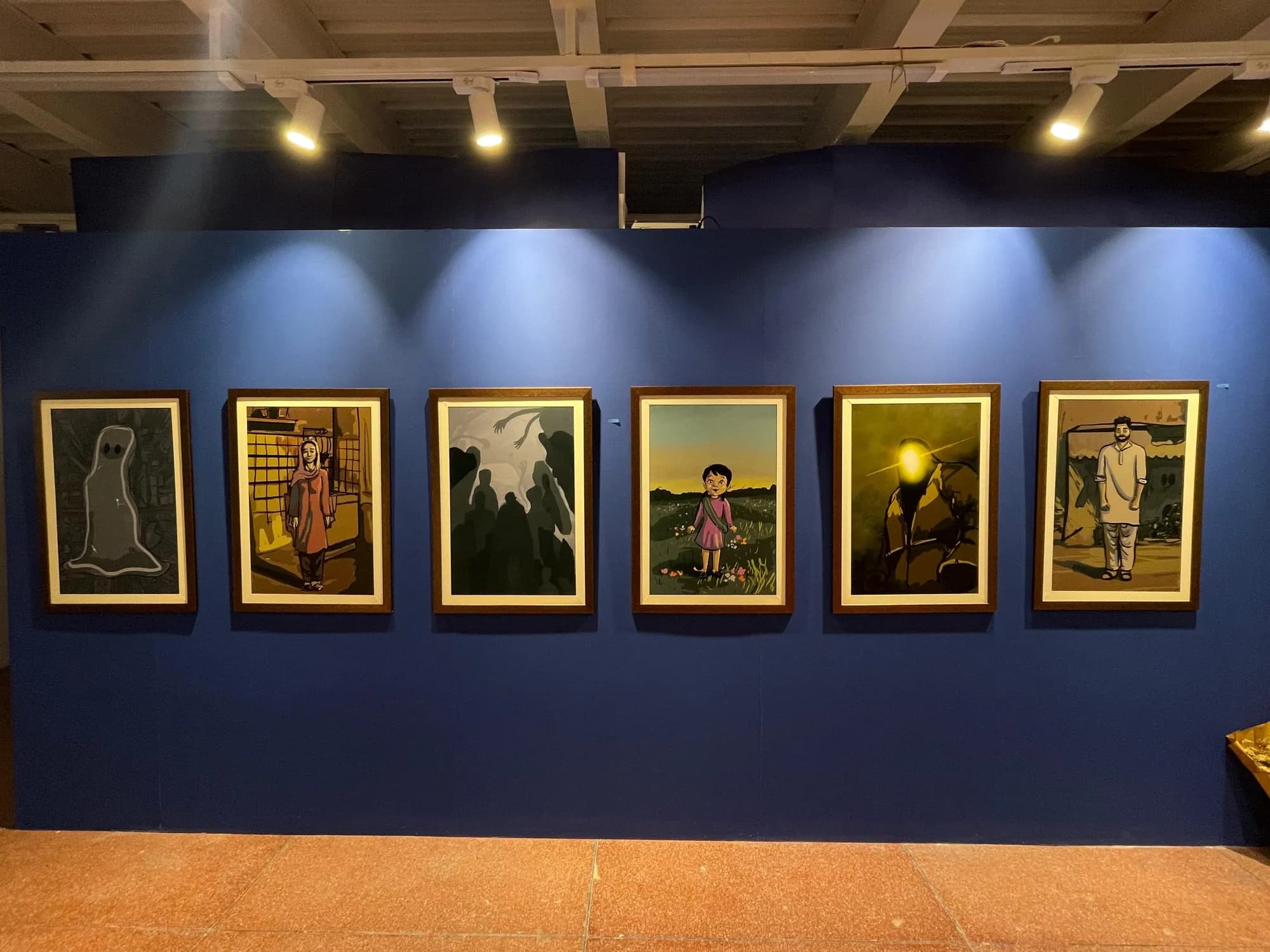 Framed Talaash artworks in a row on a deep blue gallery wall